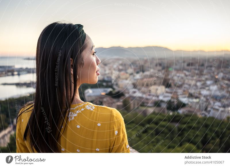 Ethnic tourist against city and sunset sky woman tourism smile sea ethnic castillo gibralfaro malaga spain female ruin travel trip journey coastal cityscape