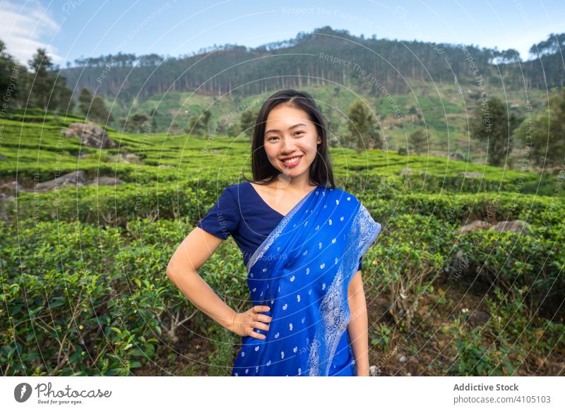 Happy charming Asian woman walking on tea fields in Sri Lanka travel traditional plantation meadow valley sari nature female agriculture enjoy worker green