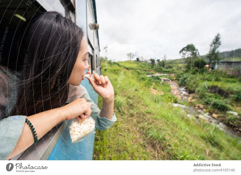 Resting Asian female taking train along green plants travel tourism woman smile enjoy laugh nature window railroad transportation journey asian trip sri lanka