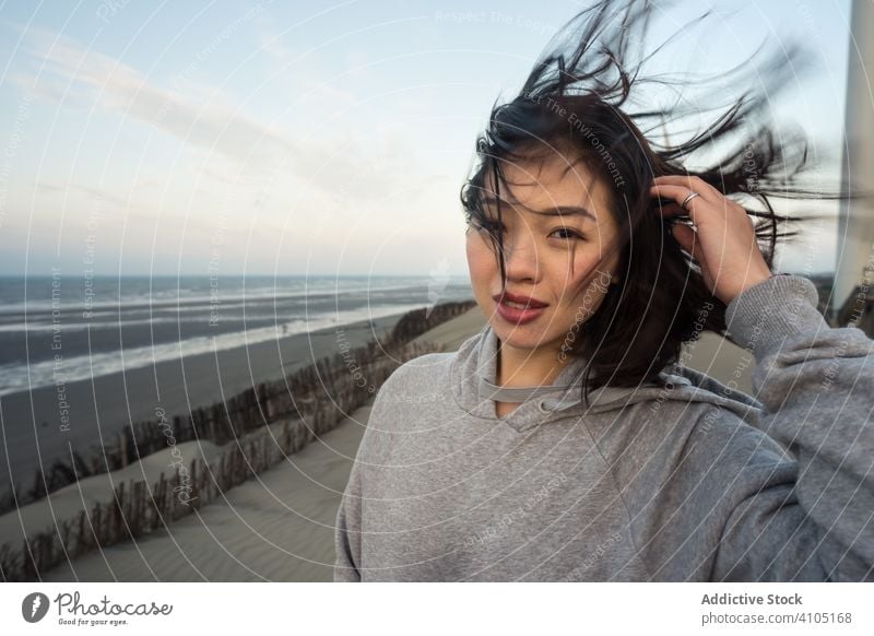 Positive Asian woman on sandy hills seashore happy windmill smile asian ethnic laughing enjoying casual travel vacation resting relaxing female summer taiwan