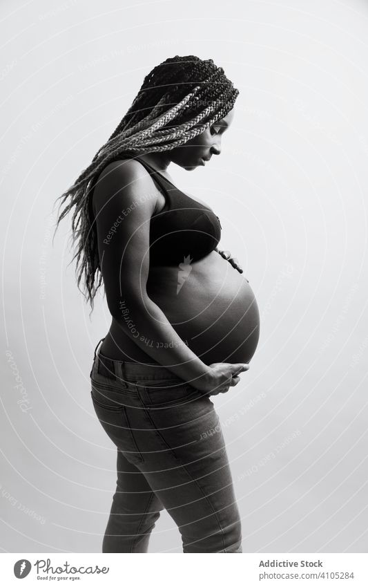 Happy African American pregnant woman holding hands on belly touching happy cheerful expecting maternity motherhood pregnancy baby childbearing anticipation