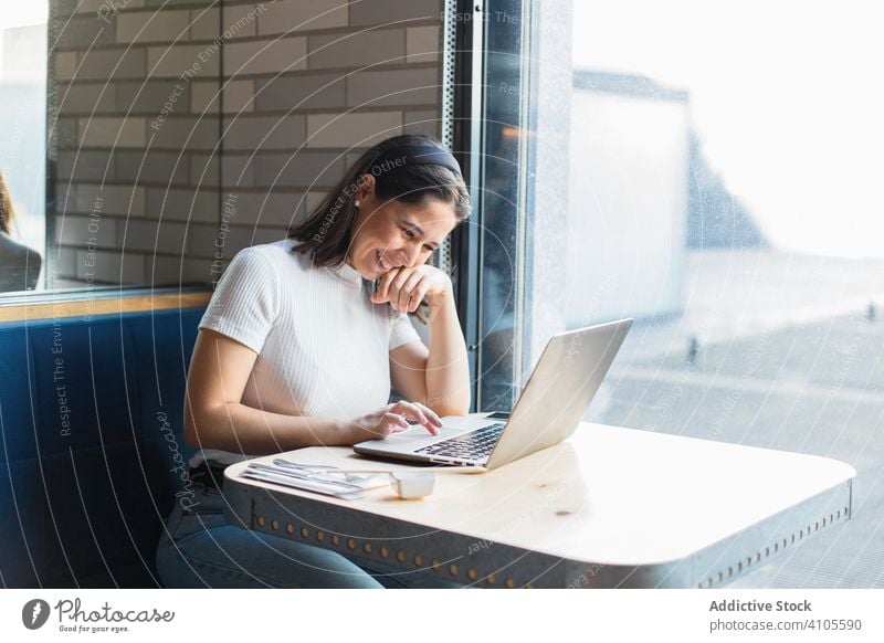 Content young woman smiling while browsing laptop in cafe using female smile laugh enjoy positive watching touch pad connection communication working modern