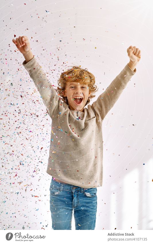 Overjoyed boy having fun with confetti at home play toss throw child male teen colorful smile enjoy laugh modern childhood lifestyle celebrate holiday festive