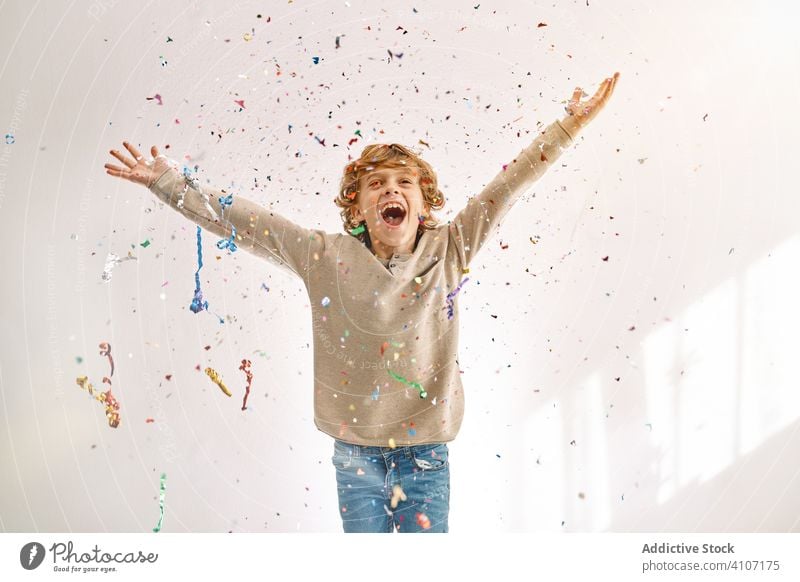 Overjoyed boy having fun with confetti at home play toss throw child male teen colorful smile enjoy laugh modern childhood lifestyle celebrate holiday festive