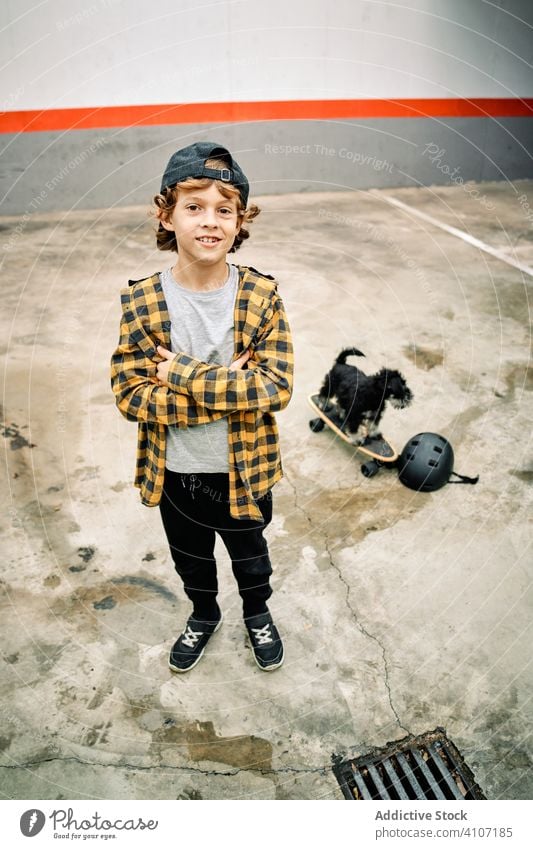 Smiling boy with dog and skateboard looking at camera skater happy pet helmet cheerful smile street building healthy recreation active hobby cool activity child