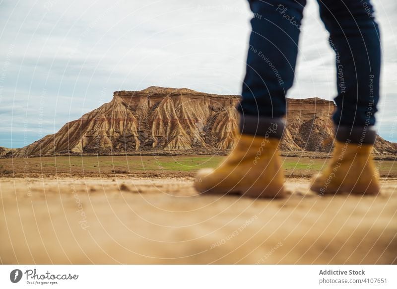 Anonymous tourist among desert with cliffs traveler tourism legs boots mountain jeans casual hill sky hiking trekking adventure nature vacation landscape