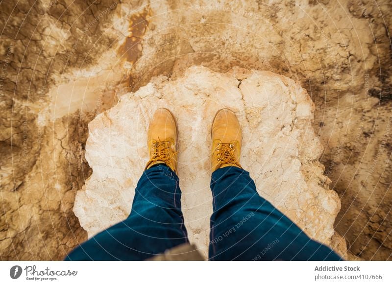 Anonymous tourist among desert with cliffs traveler tourism legs boots mountain jeans casual hill sky hiking trekking adventure nature vacation landscape