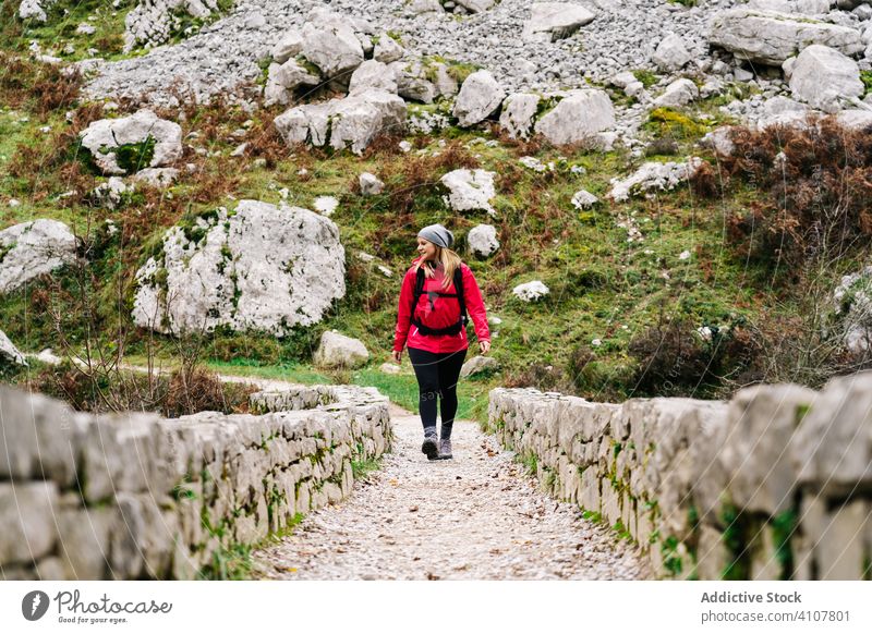 Woman walking on stone fence path among high rocks woman tourist peak female mountain hill travel nature trekking landscape tourism adventure dangerous extreme