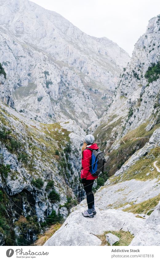 Tourist with backpack standing among high rocks woman tourist peak female mountain hill travel nature trekking landscape sky tourism adventure dangerous extreme