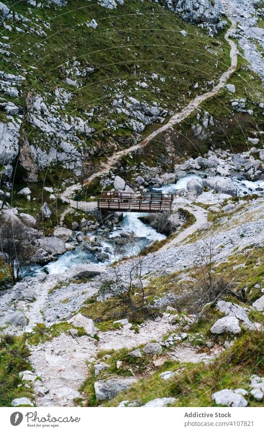 Wooden bridge above water stream flowing among rocky peaks transit mountain river scenic landscape architecture scenery wilderness adventure hill construction