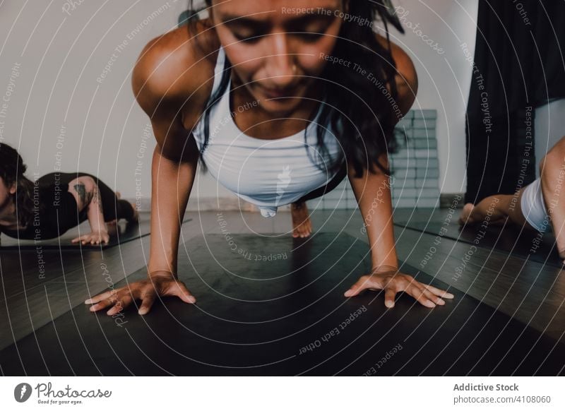 Women practicing yoga in flying pigeon position while having class in contemporary studio practice pose body barefoot training one legged plank fitness stretch