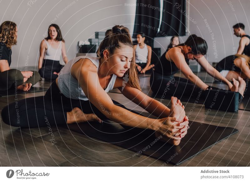 Fit female athlete stretching legs in janu sirsasana position while practicing yoga in modern studio training exercise flexible fitness workout practice people