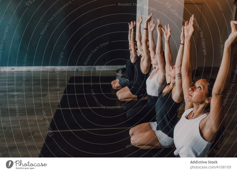 Group of calm focused athletes practicing yoga together performing hero pose in contemporary gym meditate virasana stretch gyan mudra exercise training