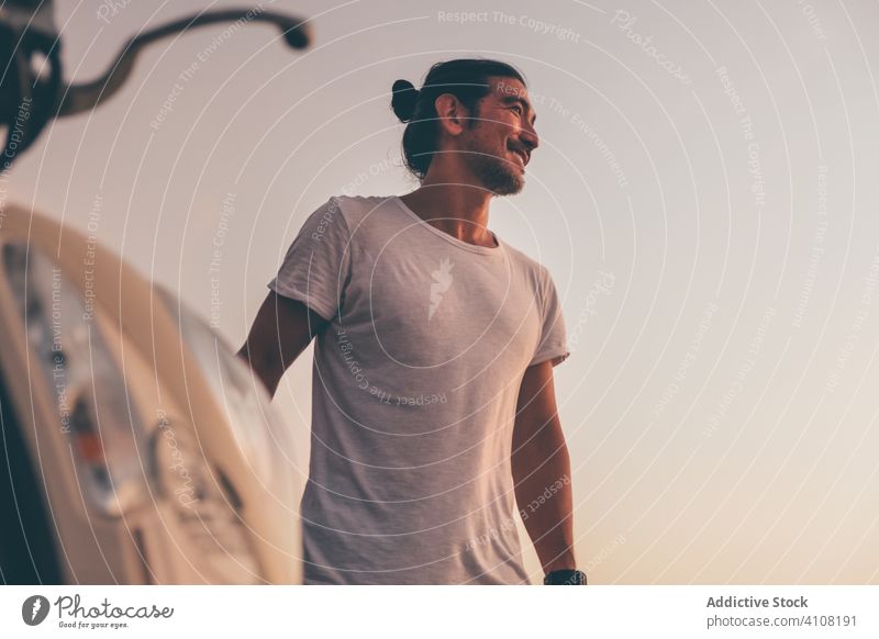 Positive man with motorbike standing at seaside happy casual relax positive sunset smile cheerful male adult rest travel summer vehicle transport lifestyle