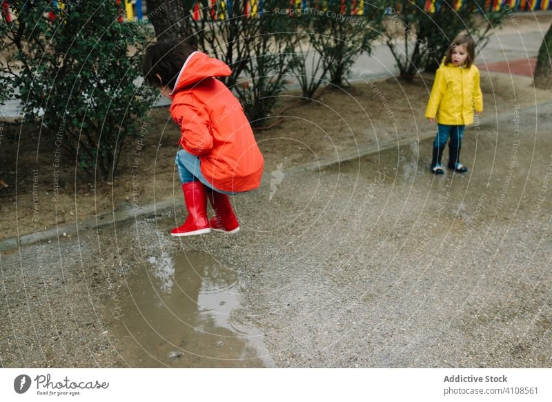 Funny kids playing in puddle in park alley children messy weather together siblings season funny water wet dirt childhood mud autumn game active rubber boots