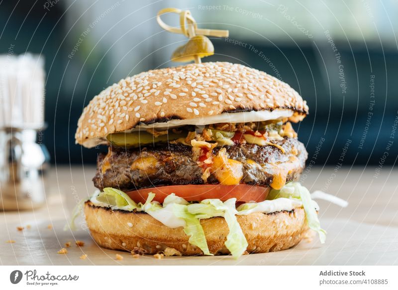 Tasty hamburger on plate in restaurant junk food snack fast food meal tasty lunch patty cutlet lettuce tomato cheese cucumber bun sesame calorie portion dish