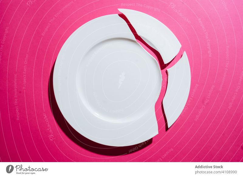 Broken white plate on pink background broken crack crockery crush fragment shard piece tableware porcelain ceramic board clean empty concept accident dish