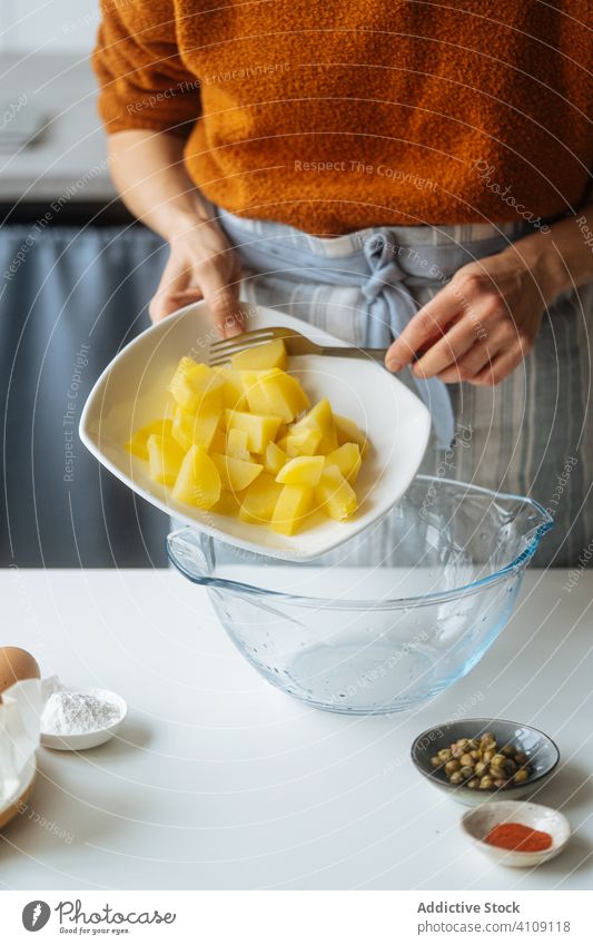 Woman putting cooked cut potato into bowl food cooking woman recipe vegetable ingredient kitchen meal healthy female housewife dinner lunch home preparation