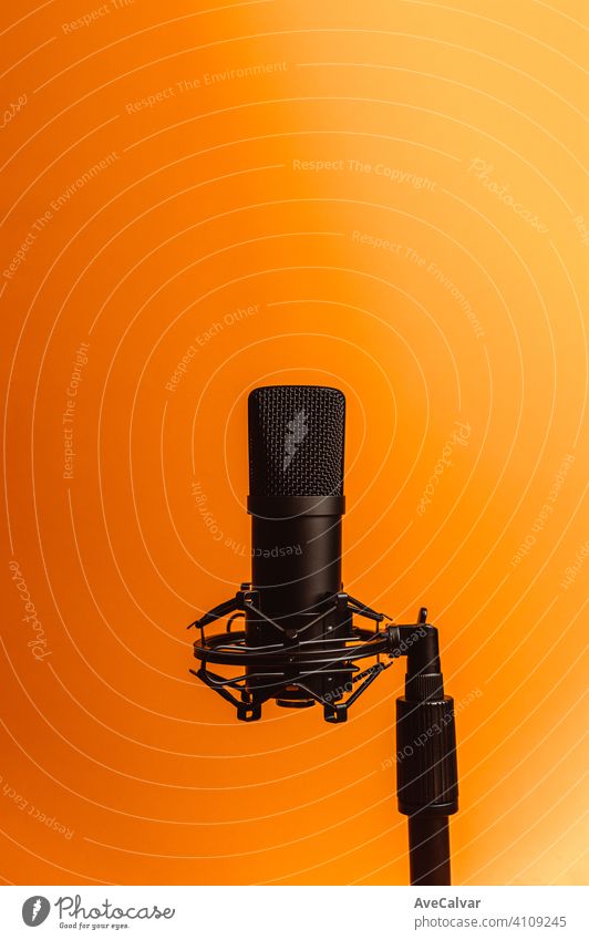 Minimalistic image of a streaming microphone over an orange background with copy space, minimal concept, technology streaming mockup pink blue streamers