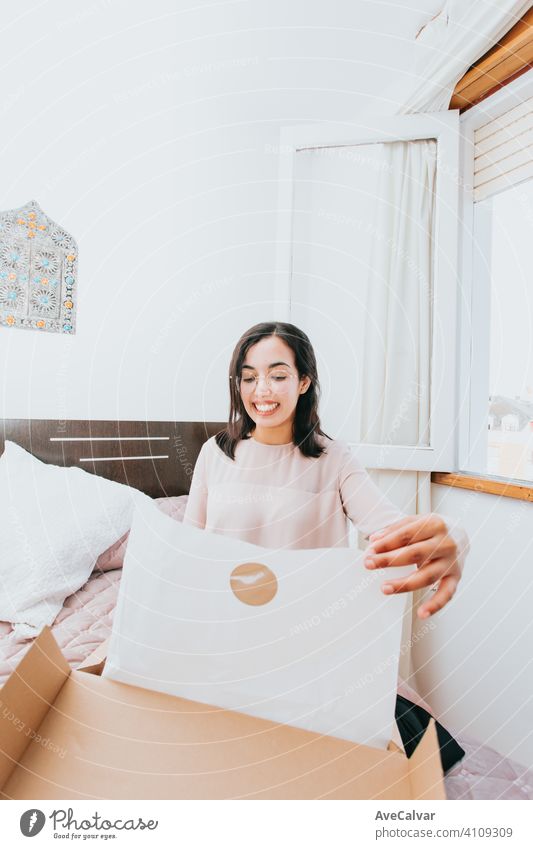 Young arab woman opening a box with products while smiling, concept retail and buying online purchase indoors delivery female shopping person customer sitting