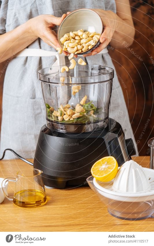 Crop woman spilling cashew into blender cook add ingredient healthy vegan kitchen dish female process nut vegetarian appliance food preparation home meal