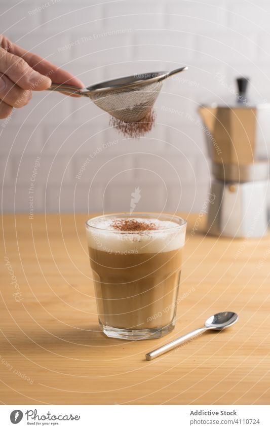 Faceless bartender garnishing coffee with cacao powder prepare service glass latte cappuccino sieve foam fresh brew milk cafe caffeine drink beverage aroma