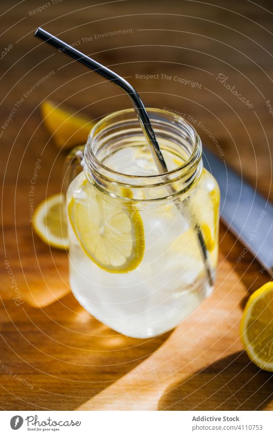 Glass jar with ice and straw on table lemon metallic reusable glass jug slice wooden eco friendly reject kitchen fresh beverage cold drink fruit lemonade water