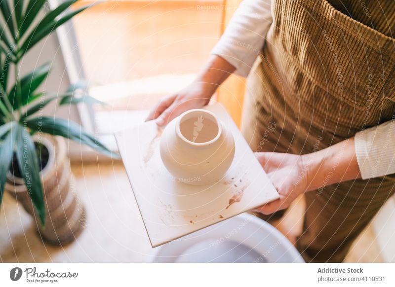 Artisan holding handmade earthenware on stand in workshop woman ceramic artisan pot craftsmanship pottery clay vase crockery utensil jug handwork home handcraft