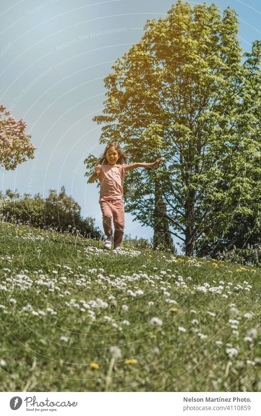 Portrait of a little hispanic girl playing and running in the park in the summer. enjoyment background day green freedom candid flower blowing activity children