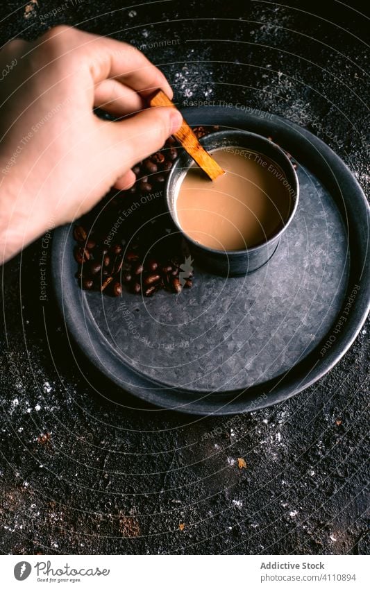 Crop person mixing coffee in cup stir spoon bean tray rustic brew fresh messy beverage breakfast caffeine drink delicious aroma rough tasty natural table liquid