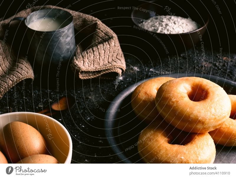 Doughnuts near ingredients on table doughnut cook kitchen recipe flour milk egg utensil pastry food napkin spoon tasty delicious bakery fresh sweet dessert