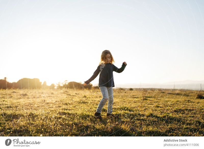 Little girl having fun in field kid happy nature child enjoy play dance sunset evening meadow countryside freedom grass summer carefree female sky childhood