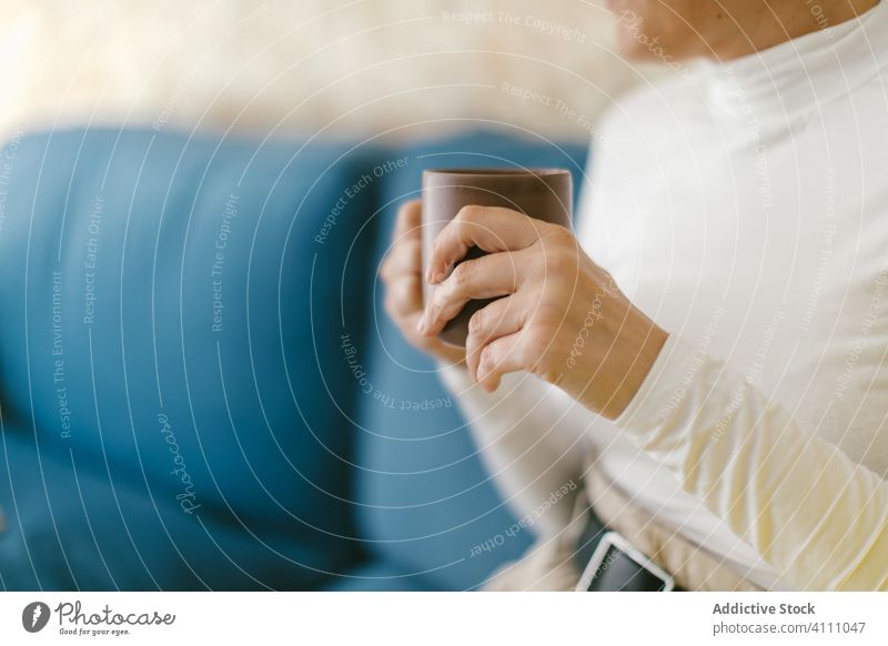 Anonymous person with coffee cup on couch woman rest business office mug chill beverage drink leisure modern casual smile adult interior tea sofa relax happy