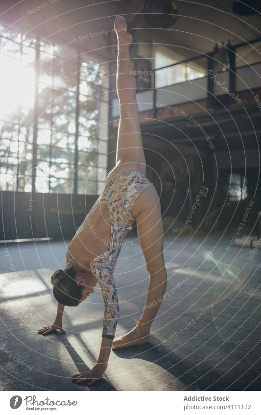 Young ballerina exercising in sunlit studio woman stretch exercise split leg up practice flexible training balance perform fit gymnastic grace activity body