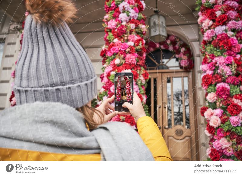 Anonymous woman taking picture of house with flower decorations smartphone take photo exterior street town shoot female memory moment capture device gadget