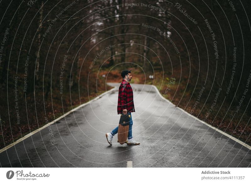 Male skater on road among autumn forest man skateboard countryside casual walk style male tree empty asphalt nature freedom adventure season way activity