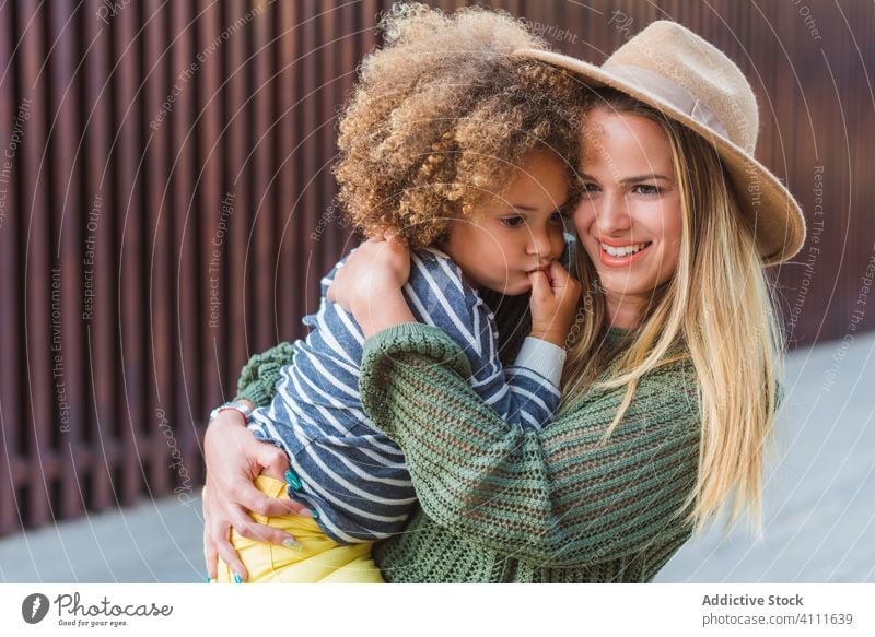 Happy mother with daughter standing in embrace on street together happy hug carry trendy urban woman modern smile cuddle relationship girl female positive mom