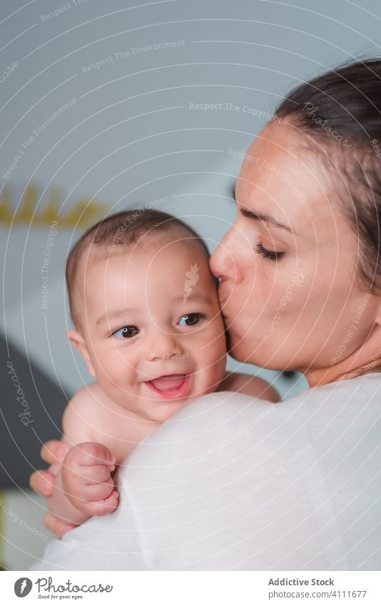 Joyful mother with baby in bedroom carry smile laugh enjoy satisfied little happy kid child adorable love cute together care tender affection hug small home