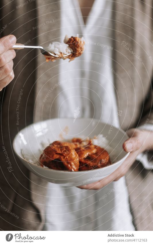 Crop woman eating curry lentil meatballs with rice vegan home dish lunch female food meal delicious tasty bowl fork portion natural culinary vegetarian diet