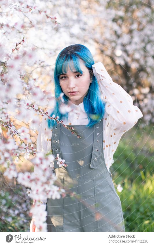 Trendy woman in blooming garden spring teen alternative dyed hair flower style trendy modern young blue hair blossom tree female nature floral beautiful season