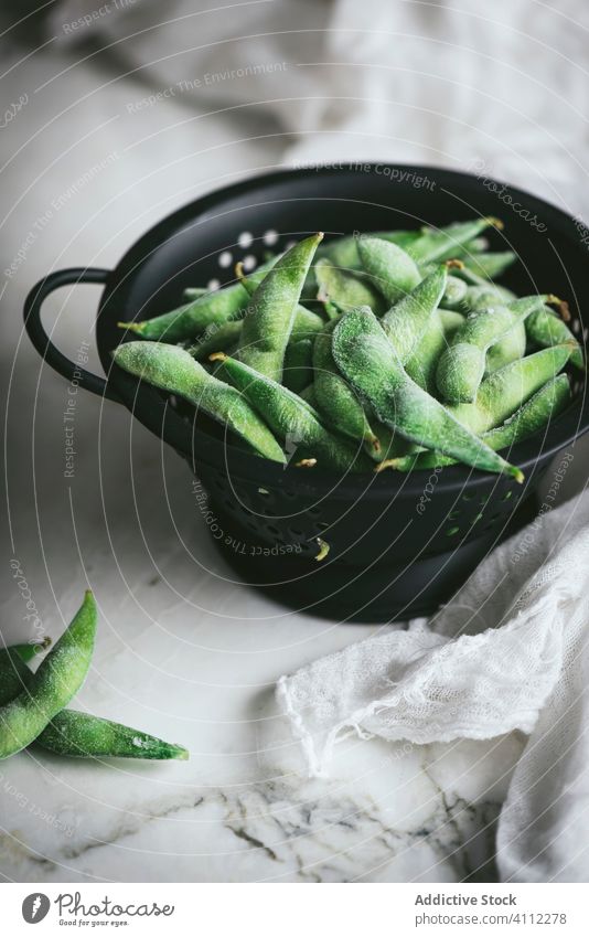 Strainer with uncooked edamames on the table strainer soybean raw unripe napkin gauze fresh food asian organic natural ingredient vegetarian vegetable vegan