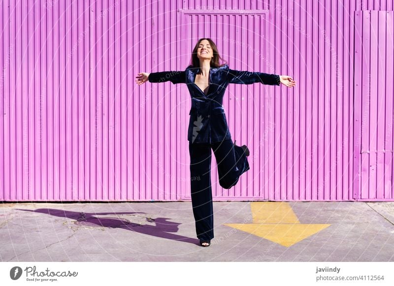 Woman wearing blue suit dancing near pink shutter. woman girl arms leg person fashion model lifestyle female urban background lady one elegant building blind