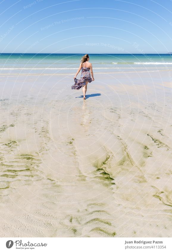 Middle-aged blonde caucasian woman in a dress walking on the beach sea summer sand relax outdoor female lady paradise quiet relaxation relaxing solitude sunny