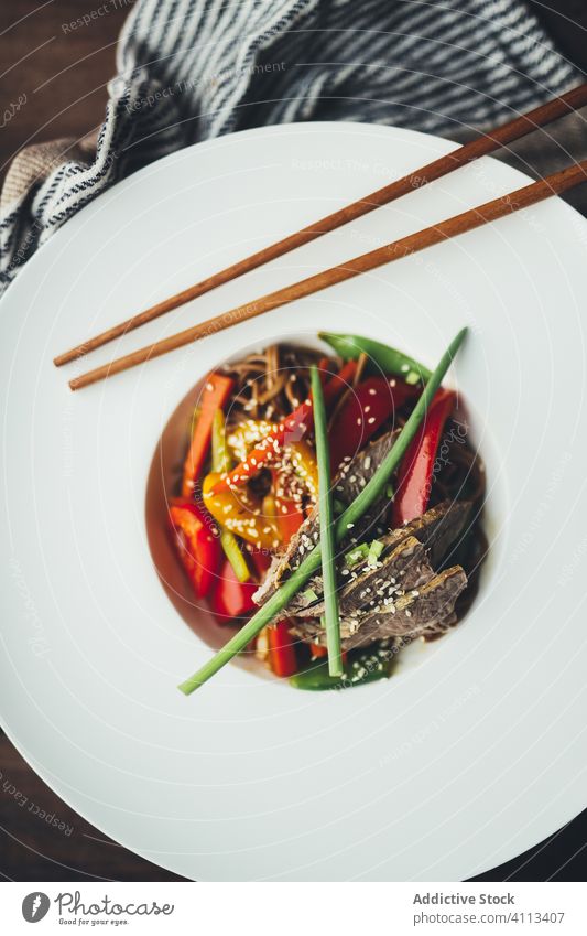 Delicious oriental noodles in white plate with chopsticks food dish asian meat vegetable tradition meal delicious wooden dinner tasty lunch cuisine healthy cook