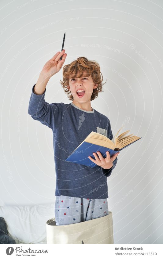 blond kid in pajamas with a book playing research children game protect happiness enjoyment room indoor party comfort emotional expression kids joyful