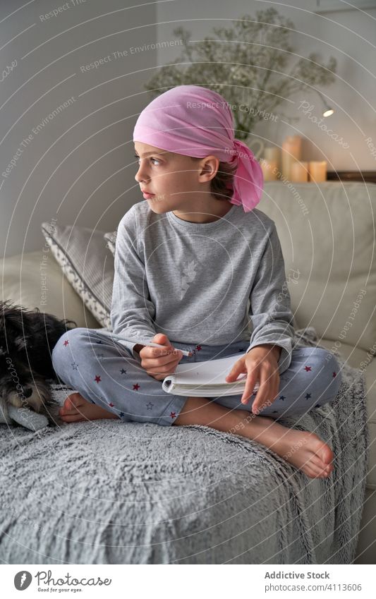 Focused little boy writing notes on bed write cancer diagnosis child home therapy male childhood faithful relax optimism awareness room pajama remission sick