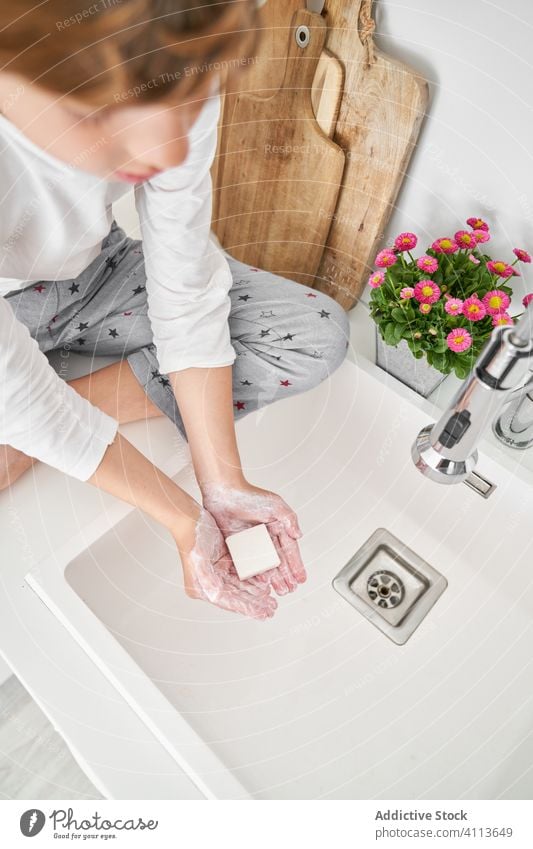 Blond child washing his hands in the kitchen sink to prevent any infection lifestyle kid indoors son boy water home young hygiene domestic childhood folding