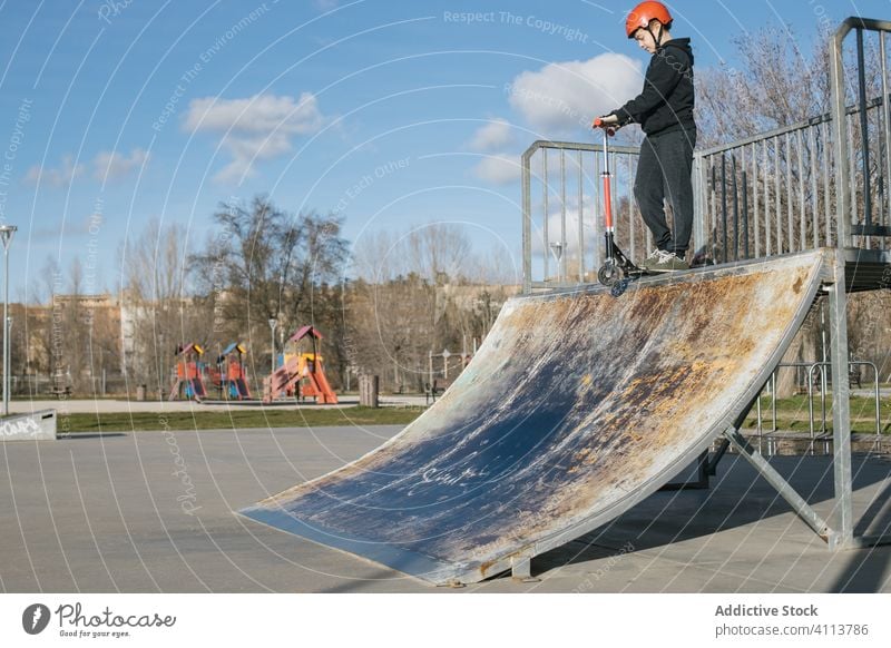 Boy riding scooter on ramp in park boy skate park extreme sport urban active practice ride kick teen teenage trick skateboard male stunt street lifestyle hobby