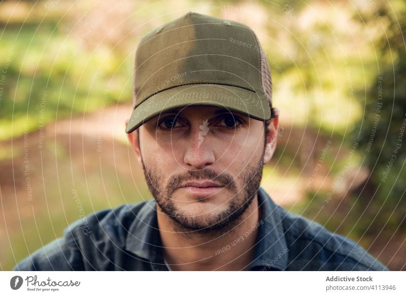 Man in checkered shirt and baseball cap in forest handsome male portrait casual man attractive hat adult person style thoughtful caucasian confident modern one