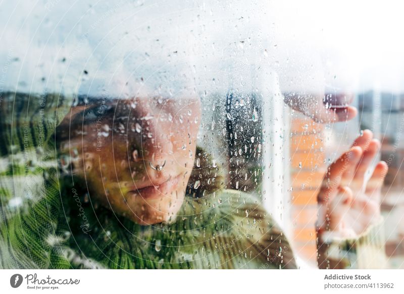 Melancholic young woman looking through window sad depression isolation coronavirus home desperate lonely unhappy female wet rain melancholy solitude stress